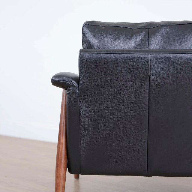 Fauteuil en cuir noir avec structure en bois style moderne.