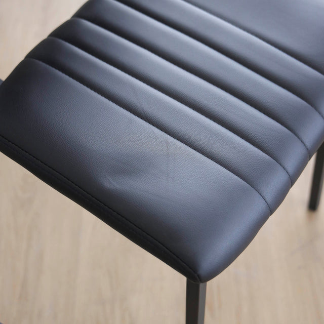 ensemble de chaises noires style vintage avec assise et dossier matelassé.