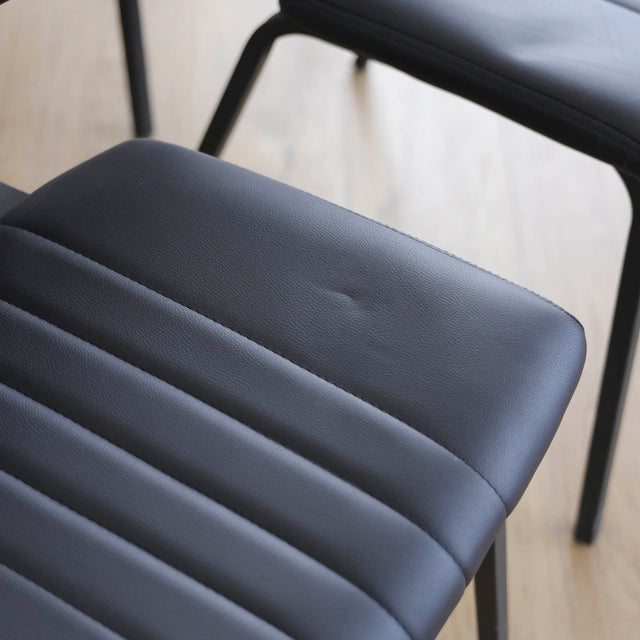 ensemble de chaises noires style vintage avec assise et dossier matelassé.