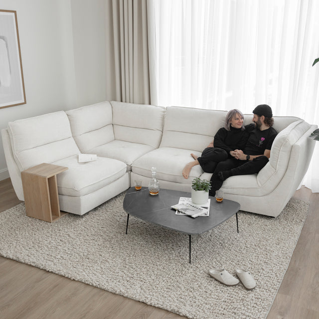 Canape sectionnel blanc moderne avec table basse noire et couple detendu sur tapis texture clair.
