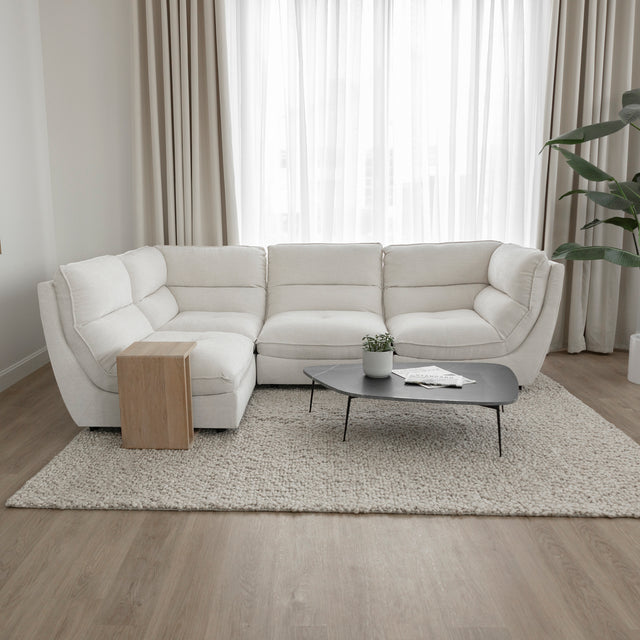 Canape sectionnel blanc moderne avec table basse noire et decor minimaliste sur tapis beige.