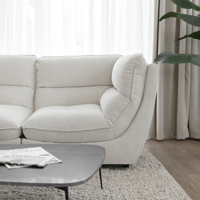 Angle du canape sectionnel blanc moderne avec table basse noire sur tapis texture clair.