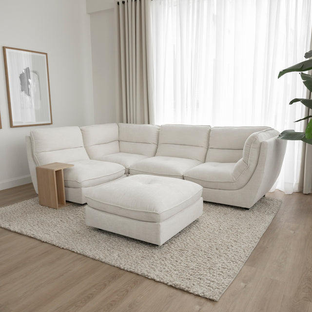 Canape sectionnel blanc moderne avec table basse noire et decor minimaliste sur tapis beige.