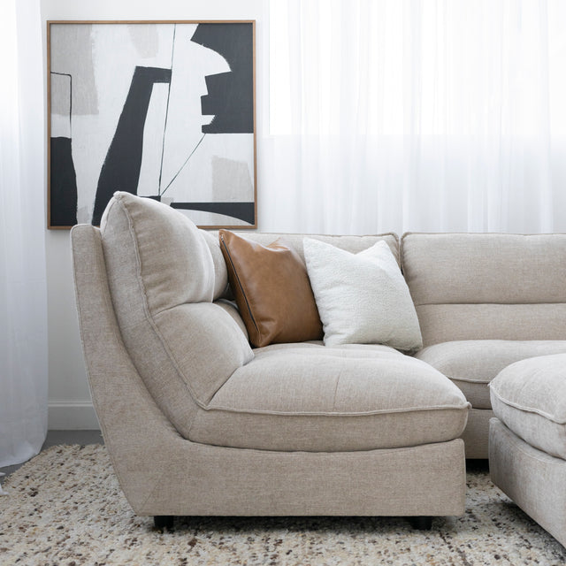 Canape beige moderne en tissu clair avec coussins decoratifs brun et creme sur tapis texture.