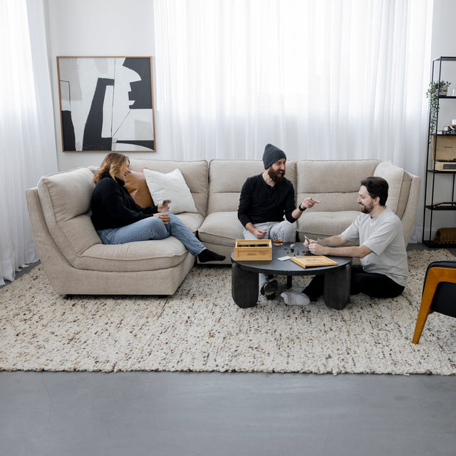 Canape sectionnel beige moderne avec table basse et amis jouant a un jeu de societe.