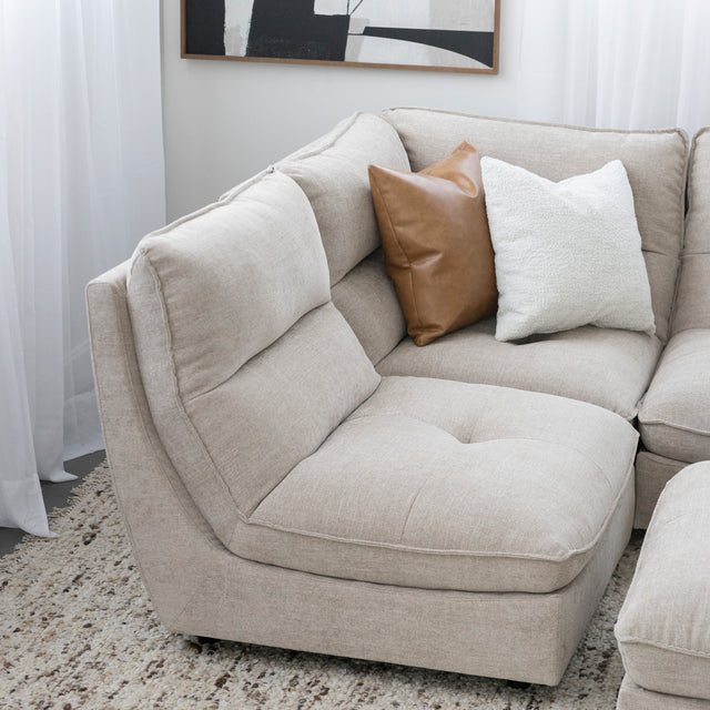 Angle du canape sectionnel beige moderne avec coussins decoratifs brun et creme.