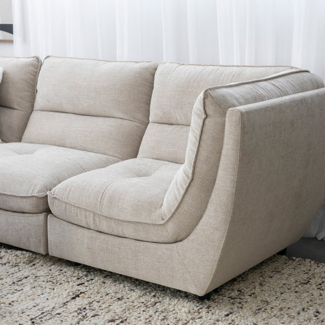 Angle du canape sectionnel beige moderne en tissu clair sur tapis texture.