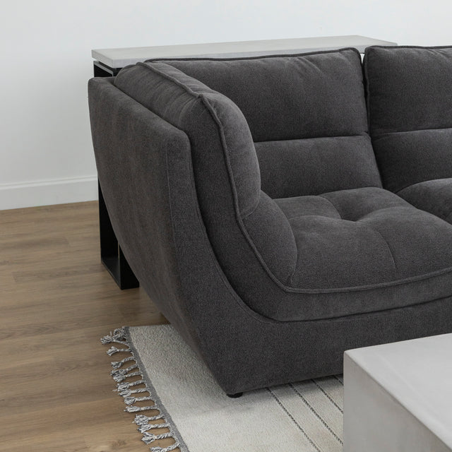 Angle du canape sectionnel gris moderne sur tapis beige avec table basse beton.