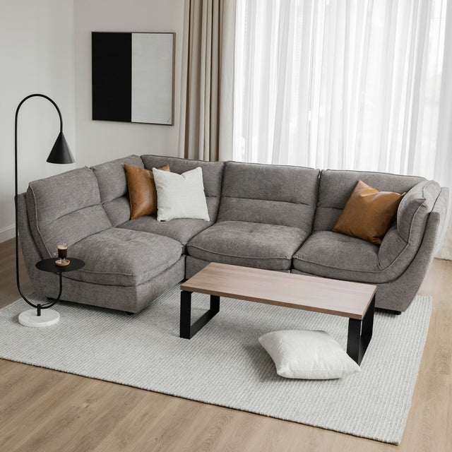 Angle du canape sectionnel gris moderne avec coussin brun et table basse bois.