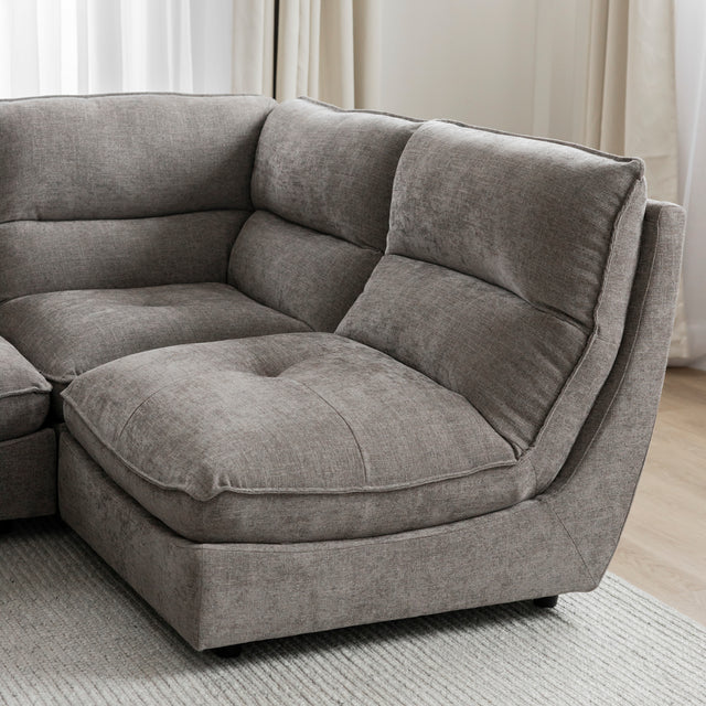 Angle du canape sectionnel gris moderne avec coussins epais sur tapis clair.