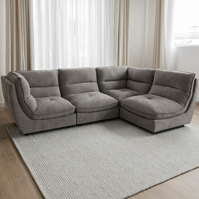 Canape sectionnel gris moderne avec assises capitonnees sur grand tapis clair.