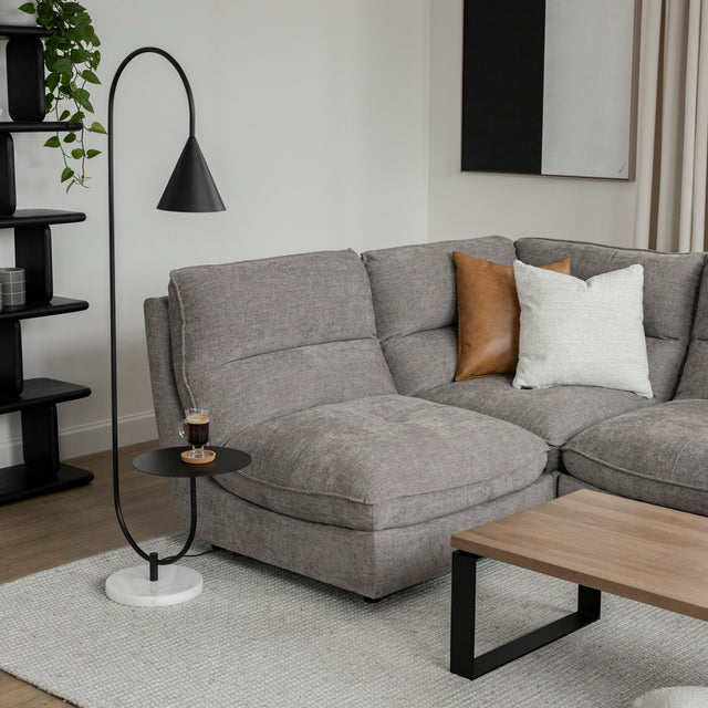 Canape sectionnel gris moderne avec coussins brun et creme, lampe noire et table basse bois.