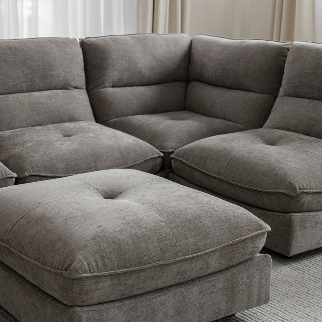 Angle du canape sectionnel gris moderne avec coussins epais sur tapis clair.