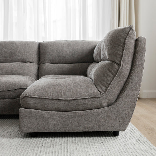 Angle du canape sectionnel gris moderne avec coussins epais sur tapis clair.