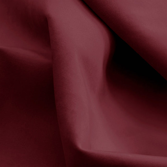 Fauteuil pivotant rouge avec repose-pieds, design moderne, dans un salon lumineux.