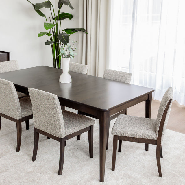 Table de salle à manger en bois foncé avec chaises rembourrées en tissu beige, style contemporain.