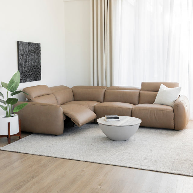 Table basse ronde en beton avec plateau effet pierre devant canape en cuir brun.