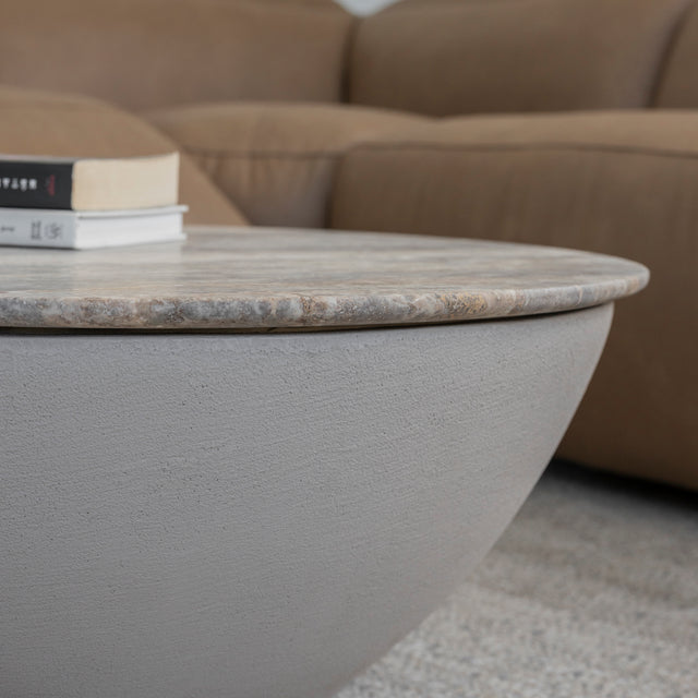 Table basse ronde en beton avec plateau en pierre beige grisee et base lisse.