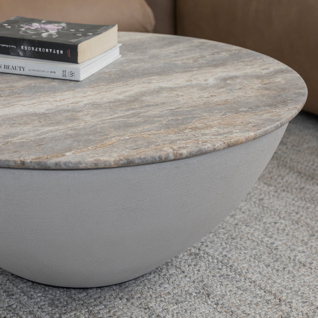 Table basse ronde en beton avec plateau en pierre beige grisee et base lisse.