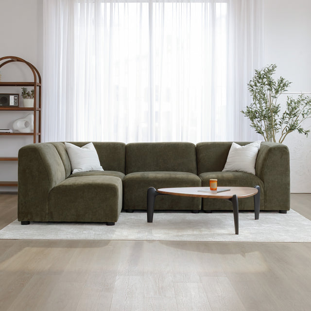 Sectionnel en tissu vert olive avec méridienne gauche, au design arrondi et contemporain dans un salon lumineux.