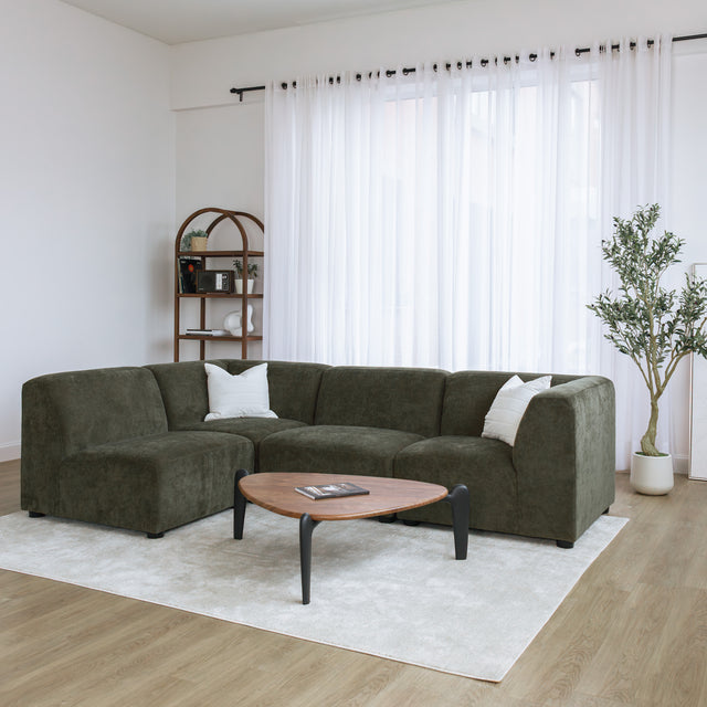 Sectionnel en tissu vert olive avec méridienne gauche, au design arrondi et contemporain dans un salon lumineux.