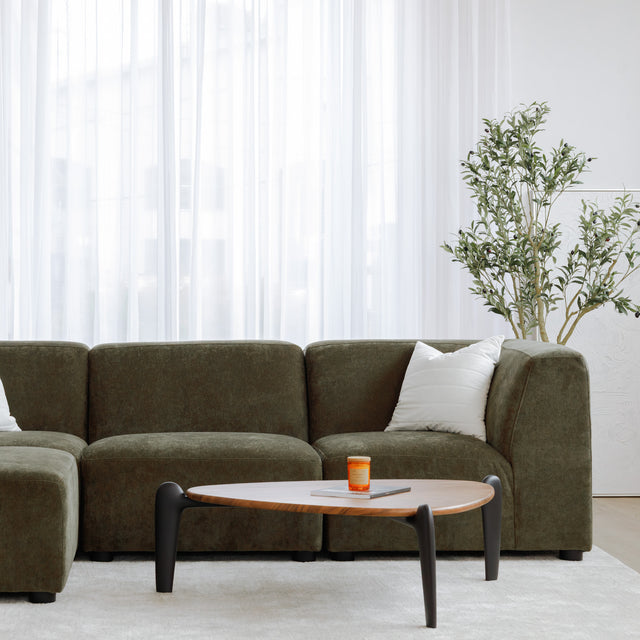 Sectionnel en tissu vert olive avec méridienne gauche, au design arrondi et contemporain dans un salon lumineux.