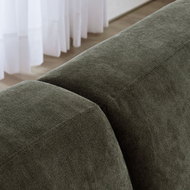 Sectionnel en tissu vert olive avec méridienne gauche, au design arrondi et contemporain dans un salon lumineux.