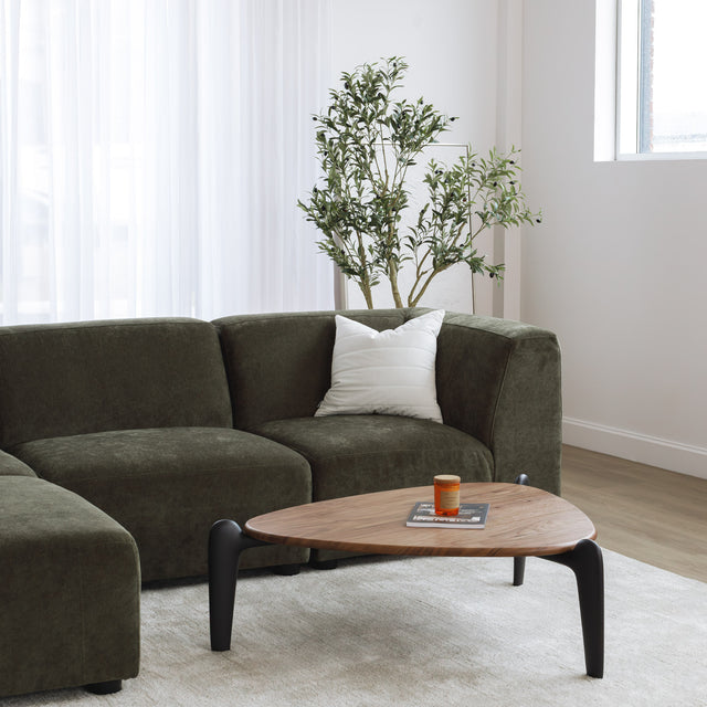 Sectionnel en tissu vert olive avec méridienne gauche, au design arrondi et contemporain dans un salon lumineux.
