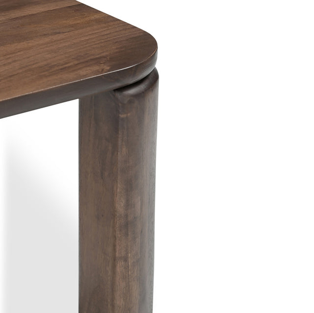 Detail du coin de table en bois fonce avec pied epais et finition arrondie.