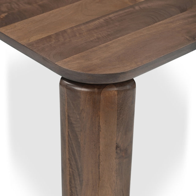 Detail du coin de table en bois fonce avec pied epais et finition arrondie.