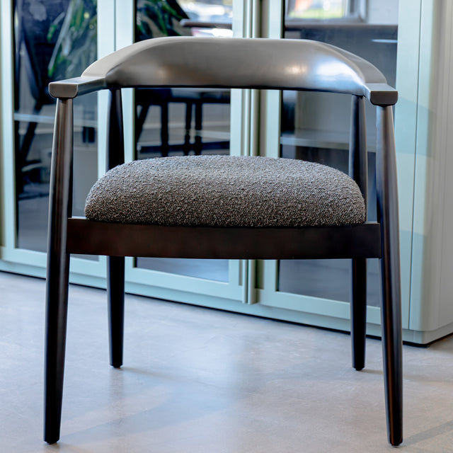 Chaise de salle à manger contemporaine avec accoudoirs noirs et assise rembourrée en tissu texturé gris.
