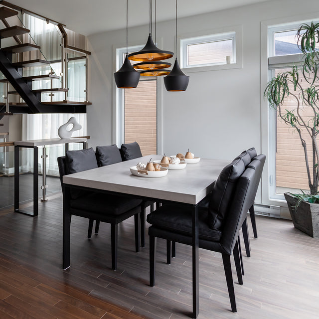 table de salle a manger en beton clair avec chaises noires et deco moderne.