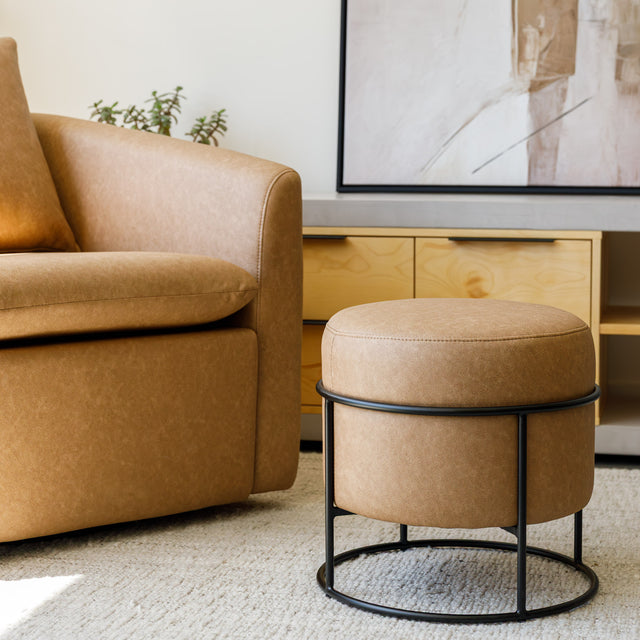 Ottoman rond en cuir végane mocha avec structure noire au style moderne et élégant.