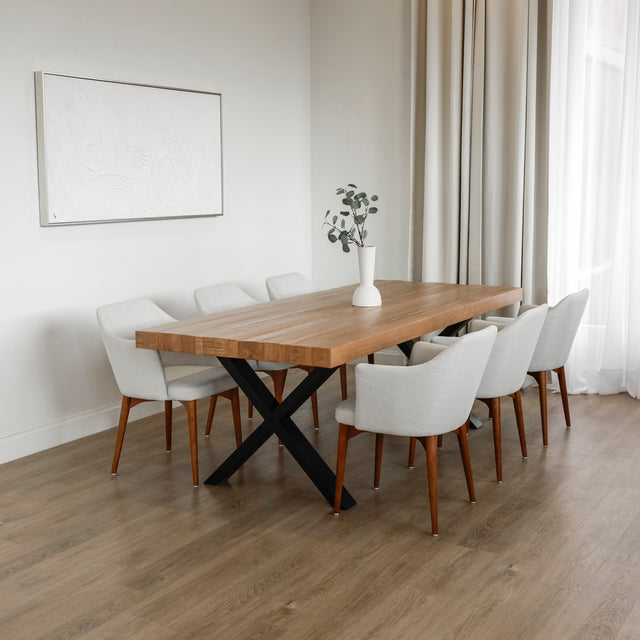 table a manger en bois massif avec pieds metalliques noirs et chaises blanches modernes dans salle lumineuse.