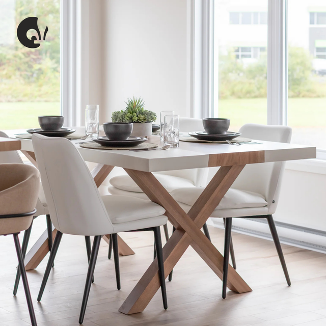Chaises de salle à manger rembourrées en cuir végane ivoire avec pieds noirs, disposées autour d’une table moderne dans un espace lumineux.