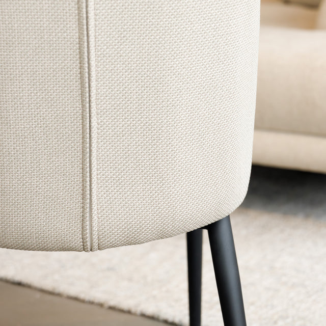 Chaise de salle à manger en tissu beige avec piètement noirs.