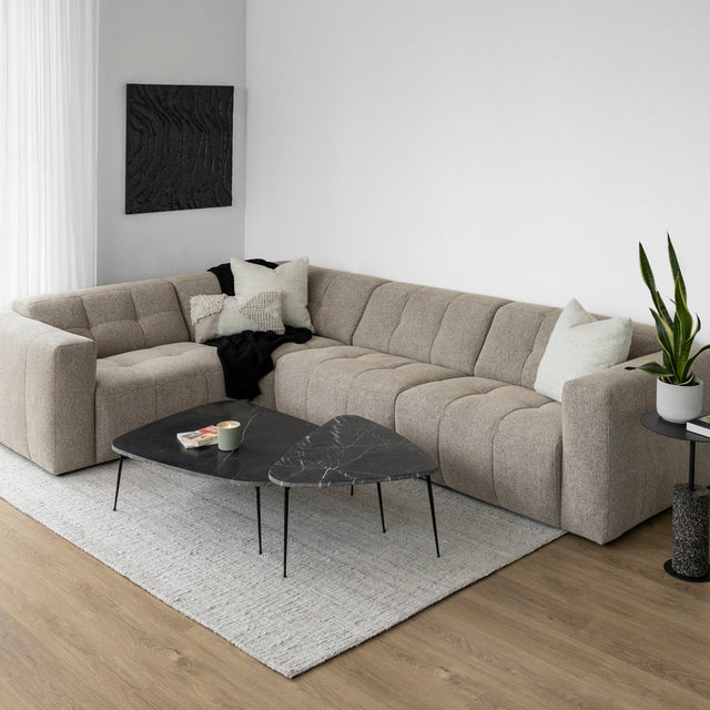 Canape d angle taupe matelasse en tissu texture avec table basse noire moderne.