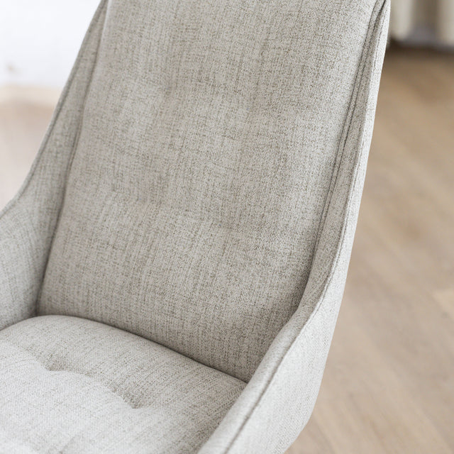 Chaise de salle à manger en tissu truffle sauvage avec piétement en bois noyer, placée près d’une table en bois moderne.