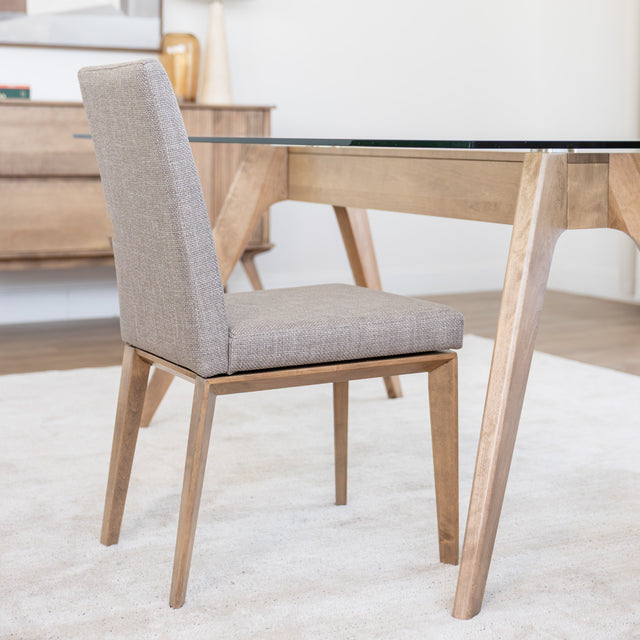 Chaise de cuisine en tissu beige avec structure en bois naturel près d’une table contemporaine.