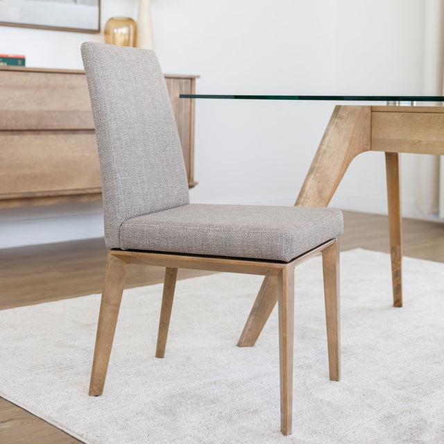 Chaise de cuisine en tissu beige avec structure en bois naturel près d’une table contemporaine.