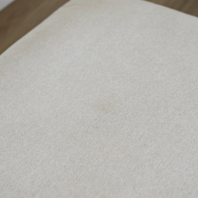 gros plan sur tissu beige clair du pouf avec legere marque sur la surface.
