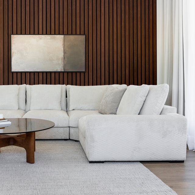 Modulaire d angle en tissu corduroy creme avec table basse en bois et decor minimaliste sur tapis clair.