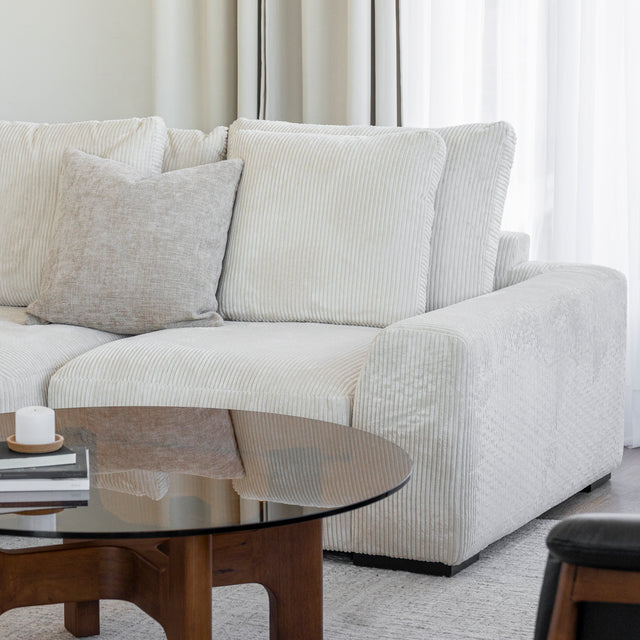 Modulaire d angle en tissu corduroy creme avec table basse en bois et decor minimaliste sur tapis clair.