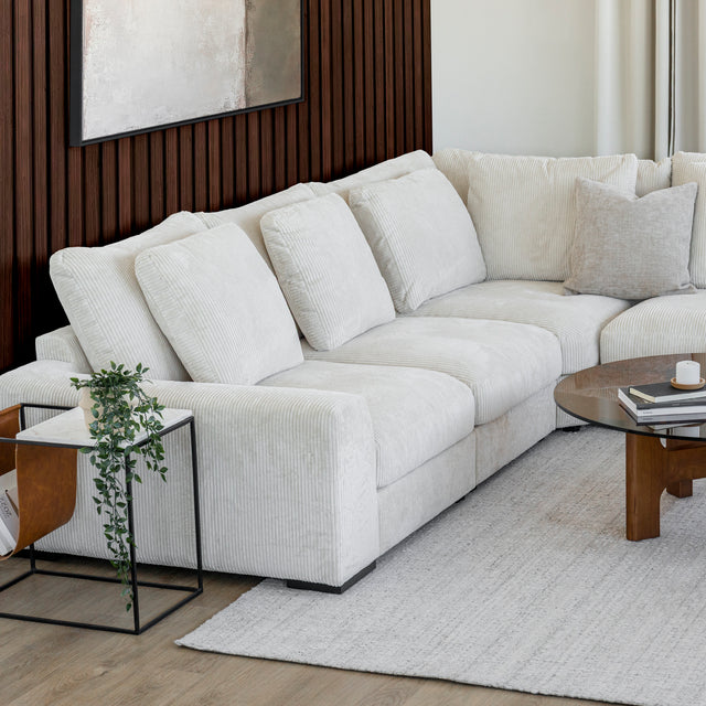 Modulaire d angle en tissu corduroy creme avec table basse en bois et decor minimaliste sur tapis clair.