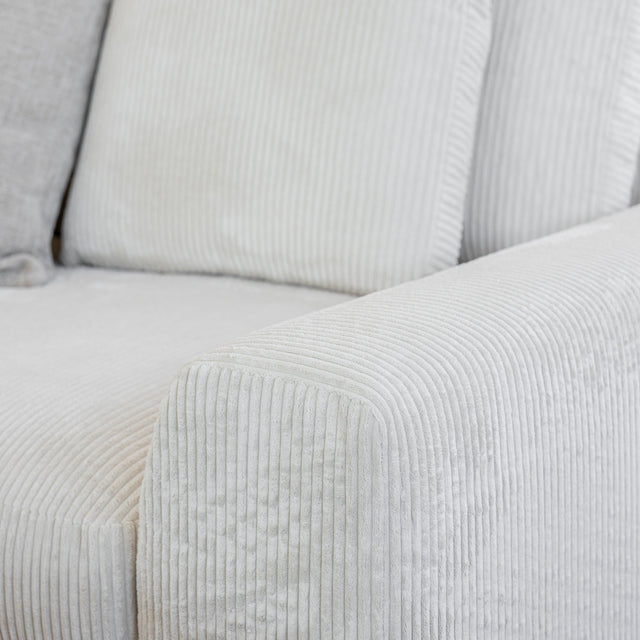 Image rapprochee Modulaire d angle en tissu corduroy creme avec table basse en bois et decor minimaliste sur tapis clair.