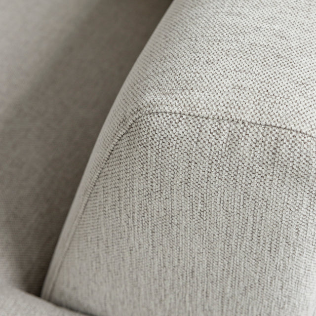 gros plan sur accoudoir de canape beige clair en tissu texture fin.