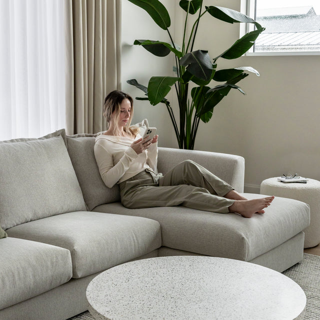 canape beige clair moderne avec personne assise utilisant son telephone.