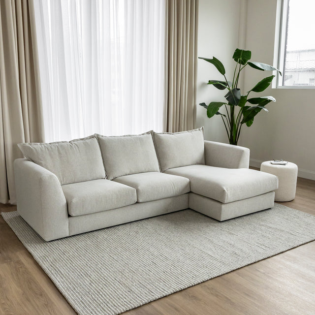 canape beige clair avec meridienne dans salon moderne sur tapis creme.