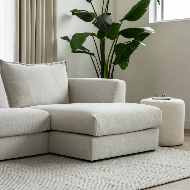 canape beige clair avec meridienne sur tapis creme et plante verte decor.