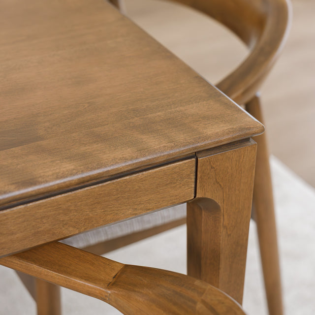 Table de cuisine en bois avec chaises rembourrées dans un intérieur minimaliste lumineux.